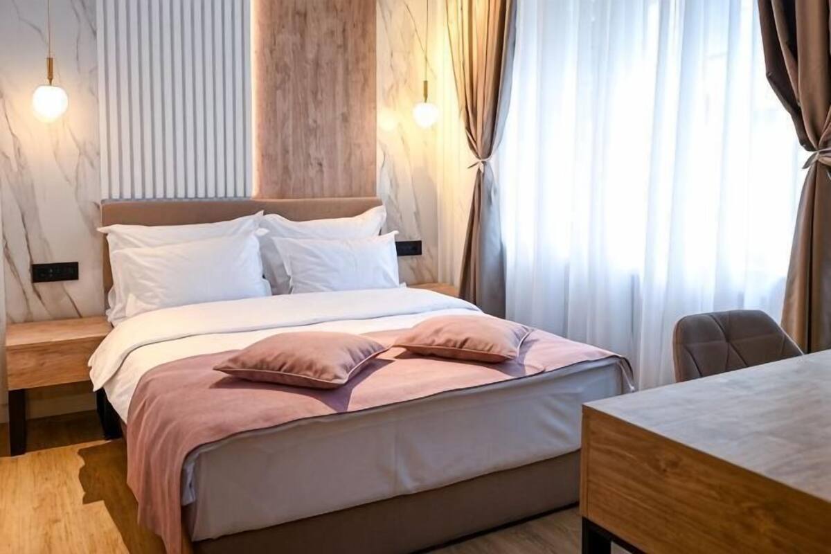 Un lit bien fait, avec des oreillers, une tête de lit en bois et une table de chevet.