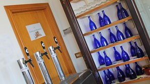Een bar met verschillende tappunten gelabeld 'Acqua Natura' en 'NATURALE', en planken vol met blauwe glazen flessen.