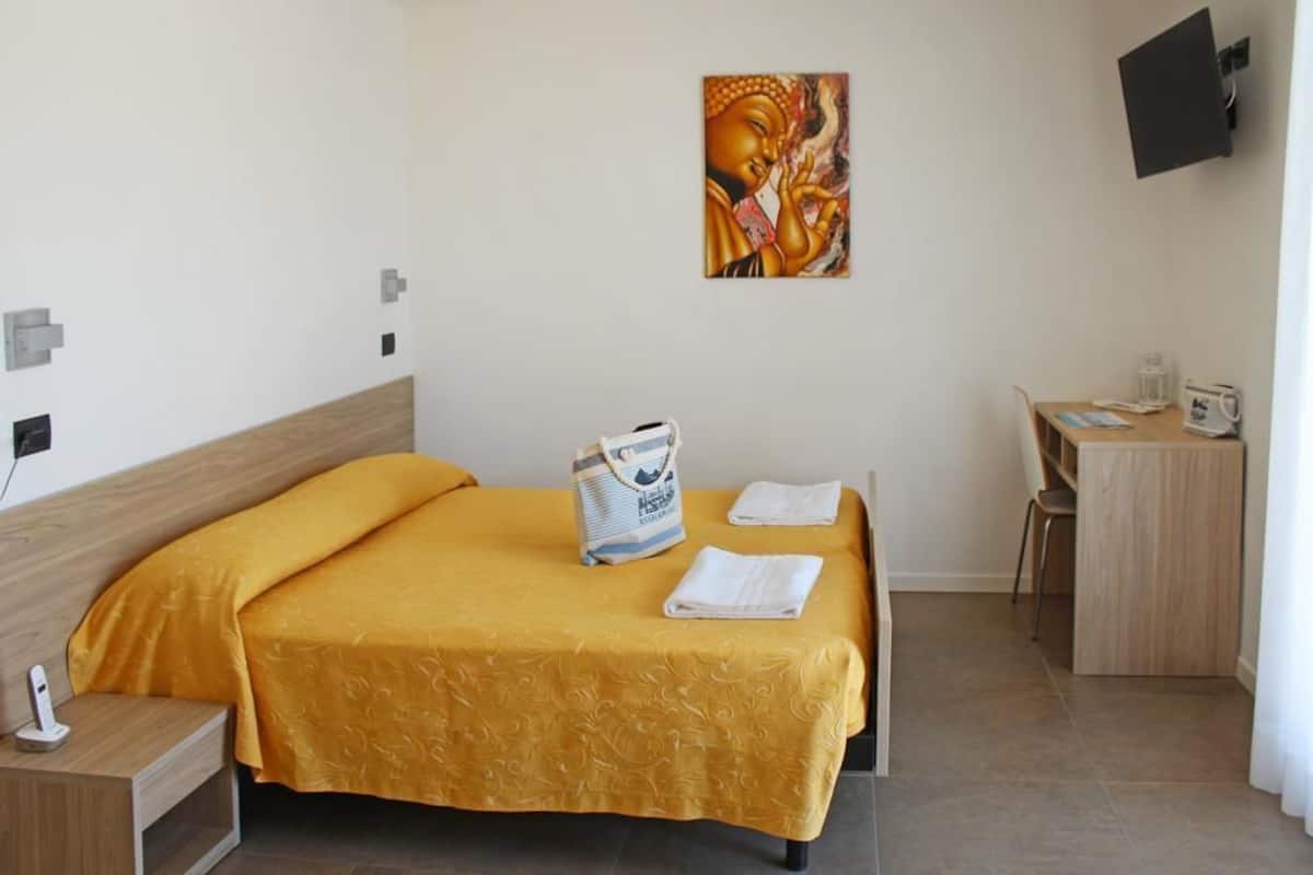 Une chambre d’hôtel avec un lit, un bureau, une chaise, une télévision et un tableau au mur.