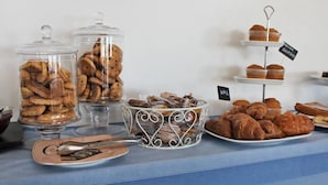 Een buffettafel met diverse gebakjes, waaronder koekjes, gebak en muffins, gepresenteerd in glazen bakken en op een etagère.