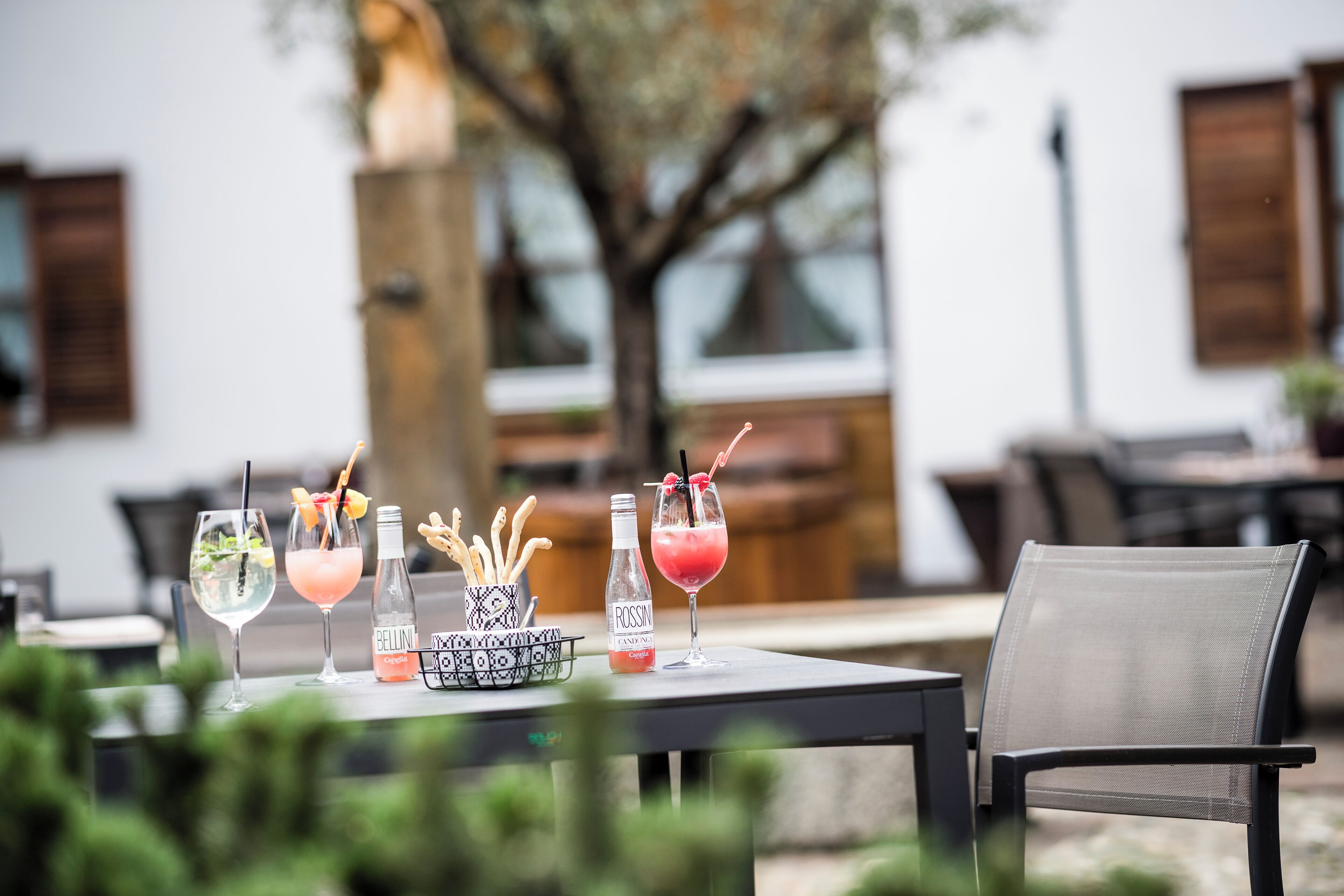 A table with three drinks, a bottle, and a basket of utensils.