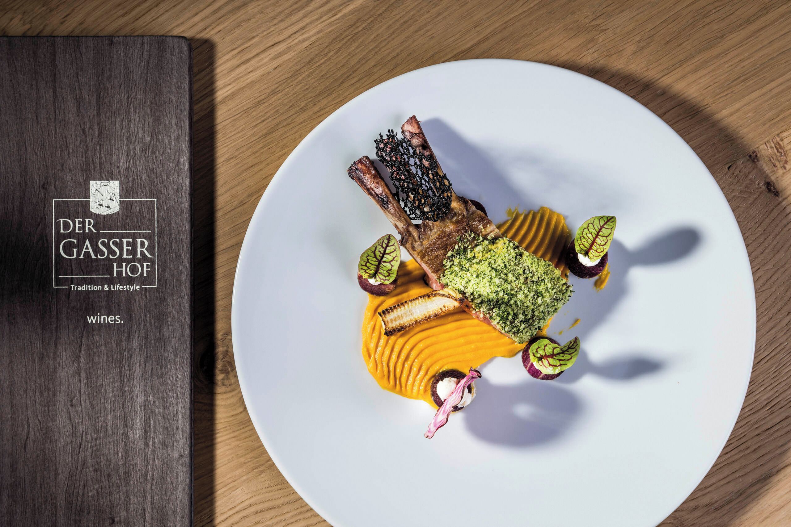 Un livre intitulé « Der Gasser Hof » est posé à côté d’une assiette contenant un plat.