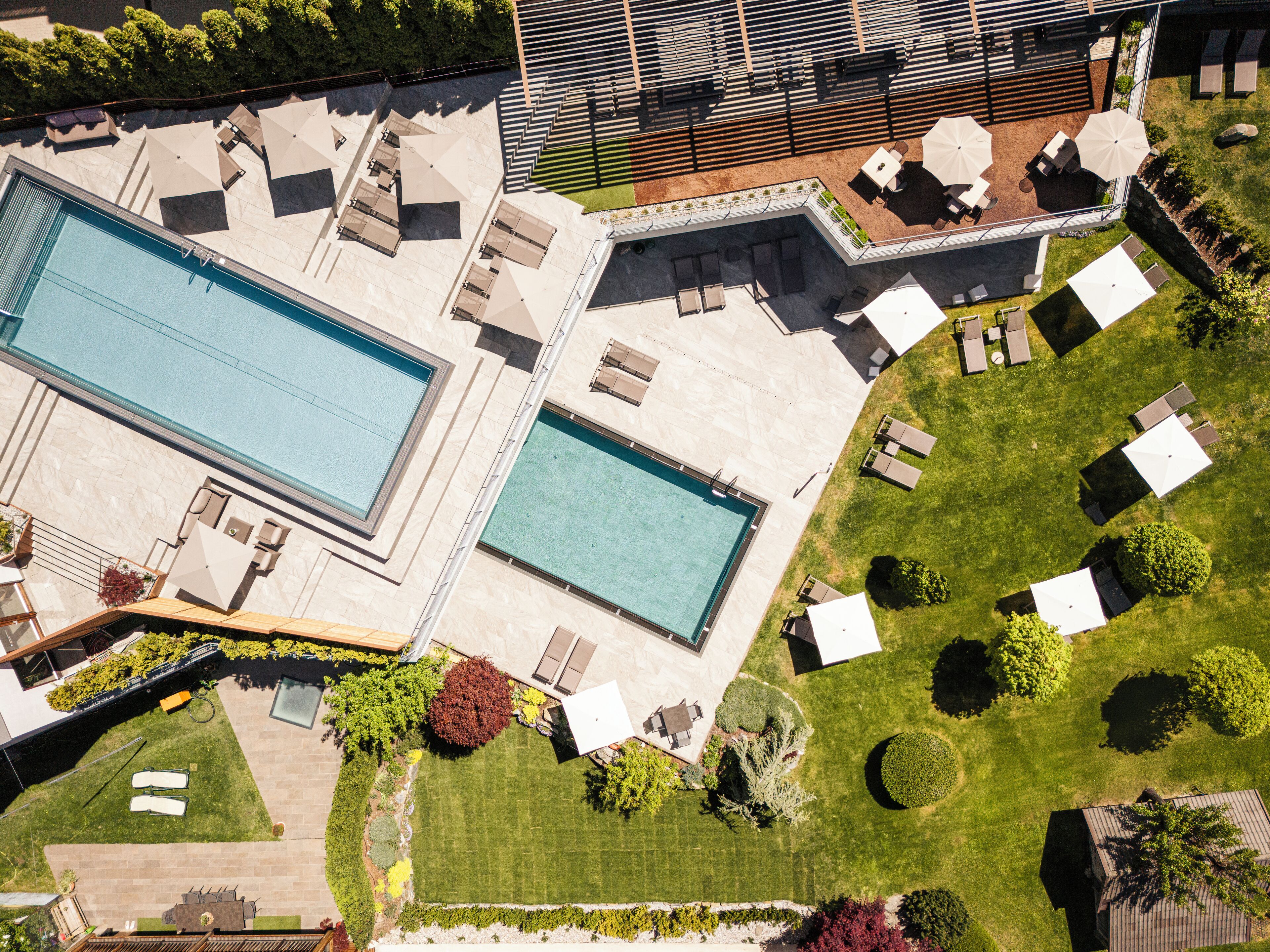 Vista aérea de un resort con dos piscinas, zonas de estar al aire libre y jardines ajardinados.