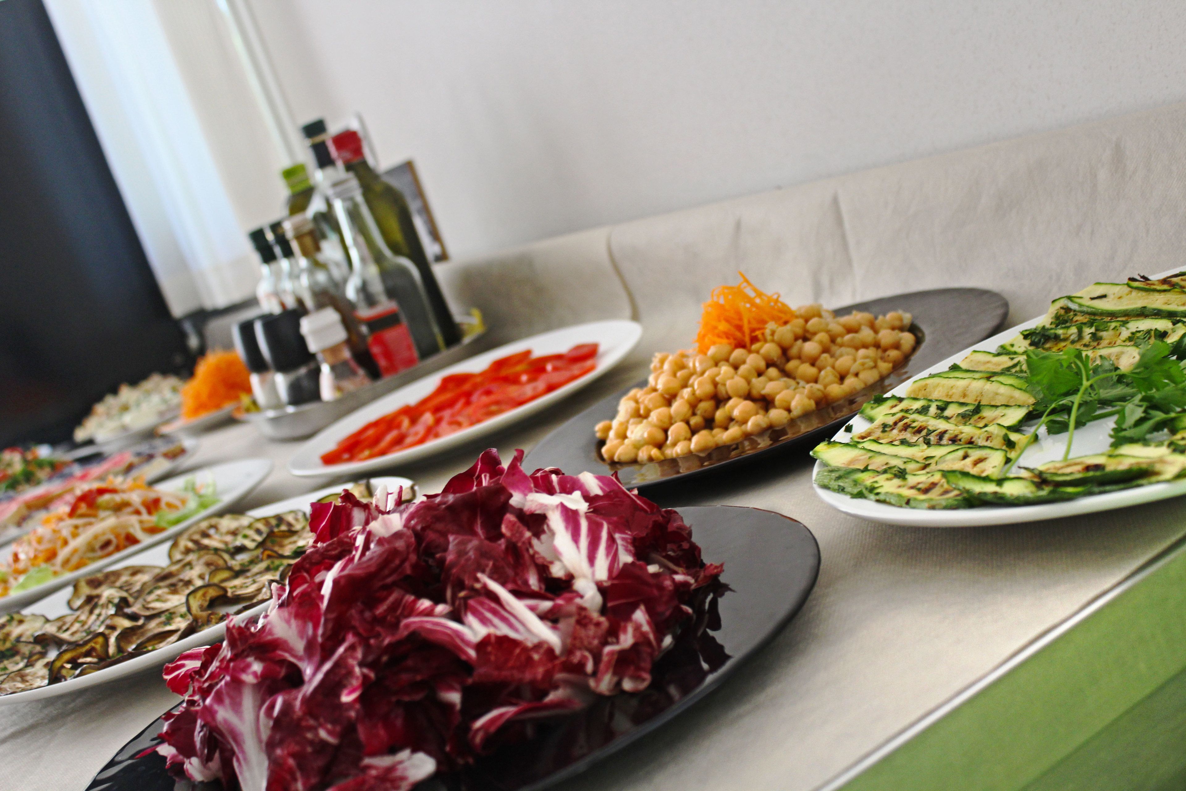 A buffet table with various dishes including salads, grilled vegetables, and chickpeas.
