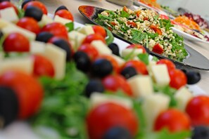 A variety of salads with tomatoes, olives, and cheese on a table.