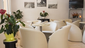Een moderne lounge met comfortabele zithoek, een aan de muur bevestigde televisie en decoratieve planten.