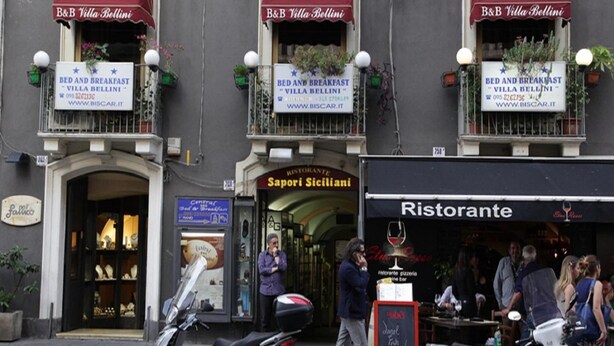 A street view with multiple storefronts, including a bed and breakfast named "Villa Bellini" and a restaurant called "Ristorante". - B&B Villa Bellini (Catania)