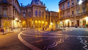 A historic square with ornate buildings, a central fountain, and cobblestone pavement. - B&B Villa Bellini (Catania)
