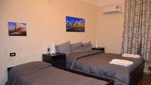 A hotel room with two beds, a nightstand, a lamp, and a wall-mounted air conditioner. - B&B Villa Bellini (Catania)