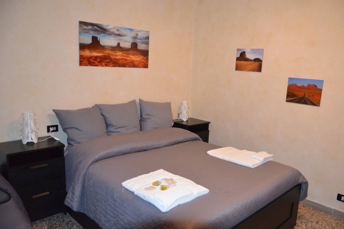 Un dormitorio con una cama grande, dos mesitas de noche y tres cuadros en la pared.