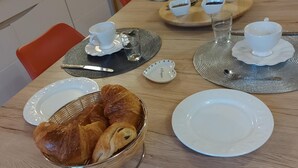 Ein Frühstückstisch mit Croissants, Tassen und einem Toaster.