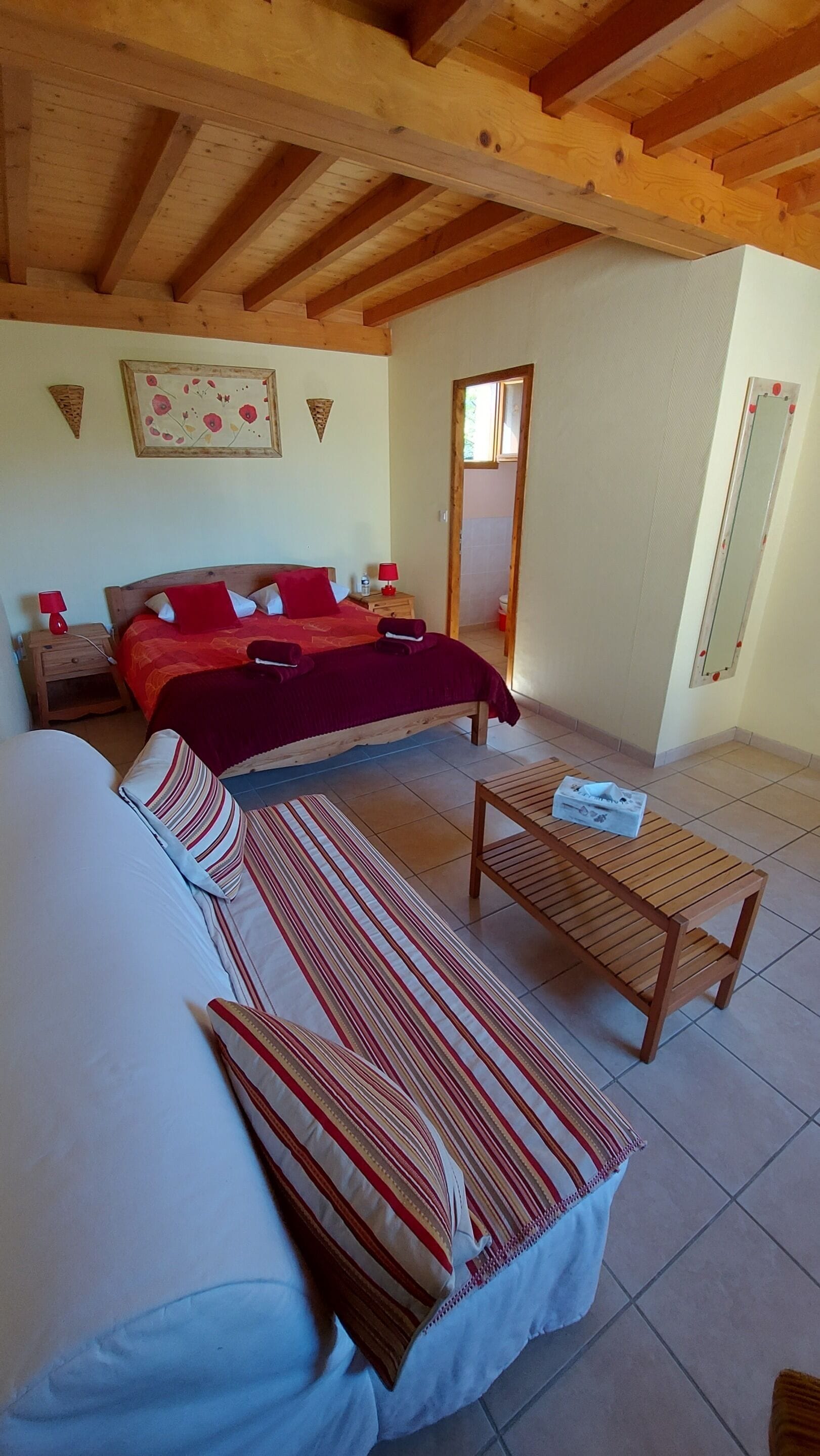 Une chambre à coucher avec un lit, un canapé, une petite table et un miroir.