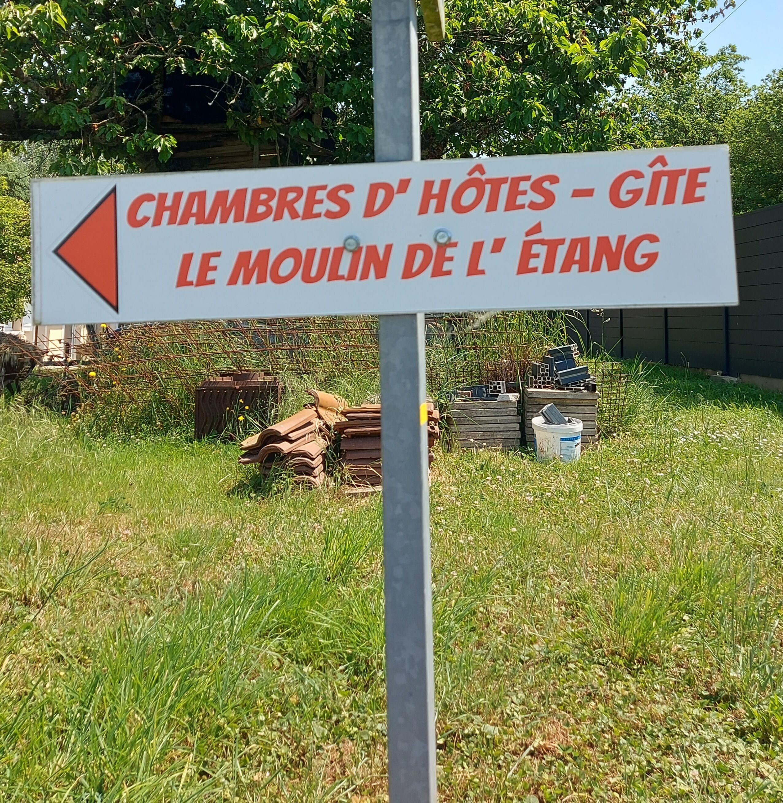 A directional sign with text in French, pointing towards 'Chambres d'Hôtes - Gîte le Moulin de l'Étang'.
