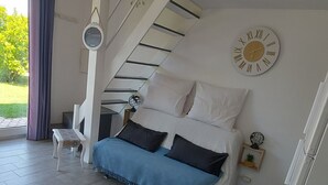 Ein modernes Schlafzimmer mit einem Bett, einem kleinen Tisch, einer Uhr und einer Treppe.
