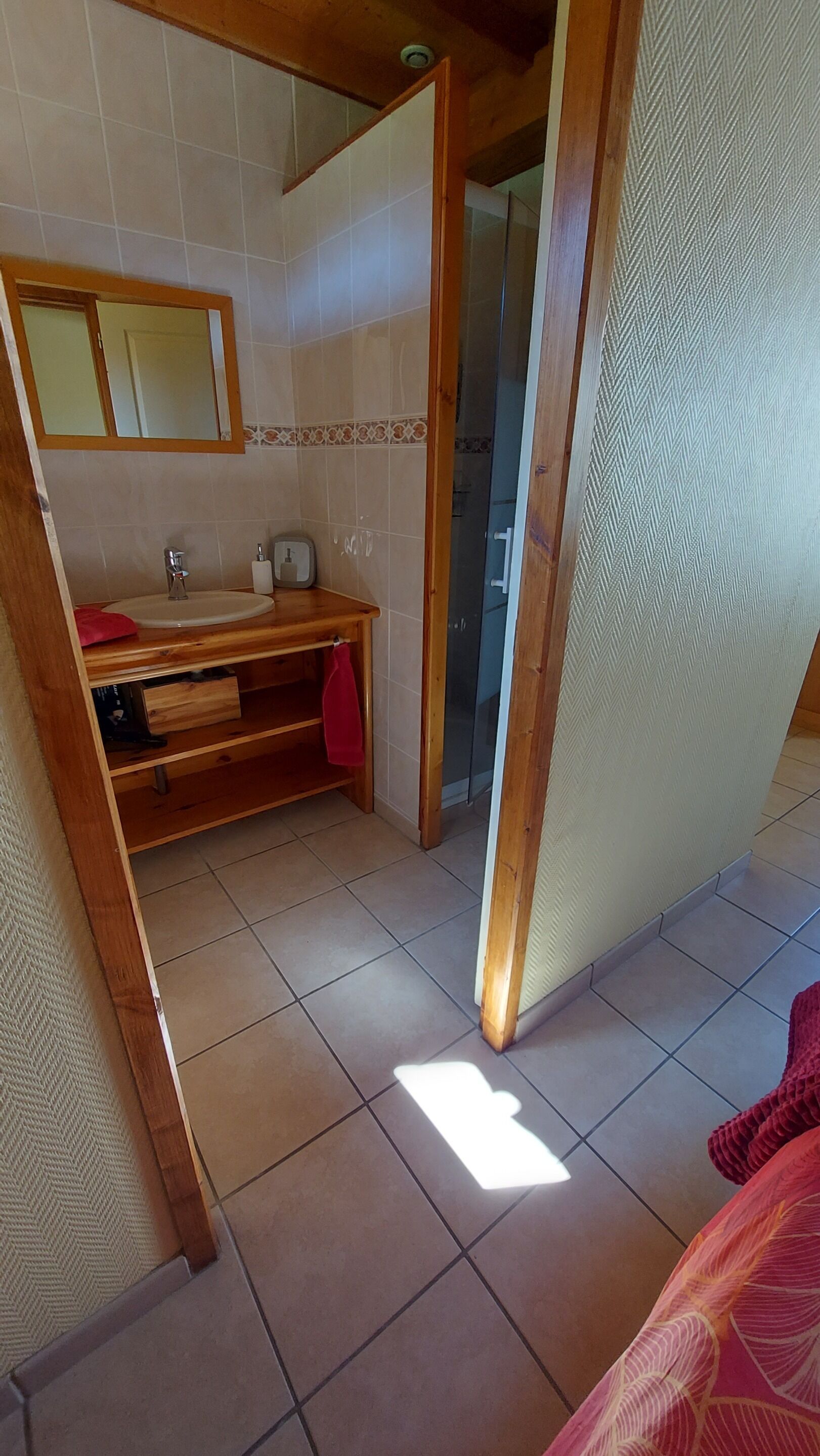 A bathroom with a wooden vanity, a mirror, a toilet, and a shower area.