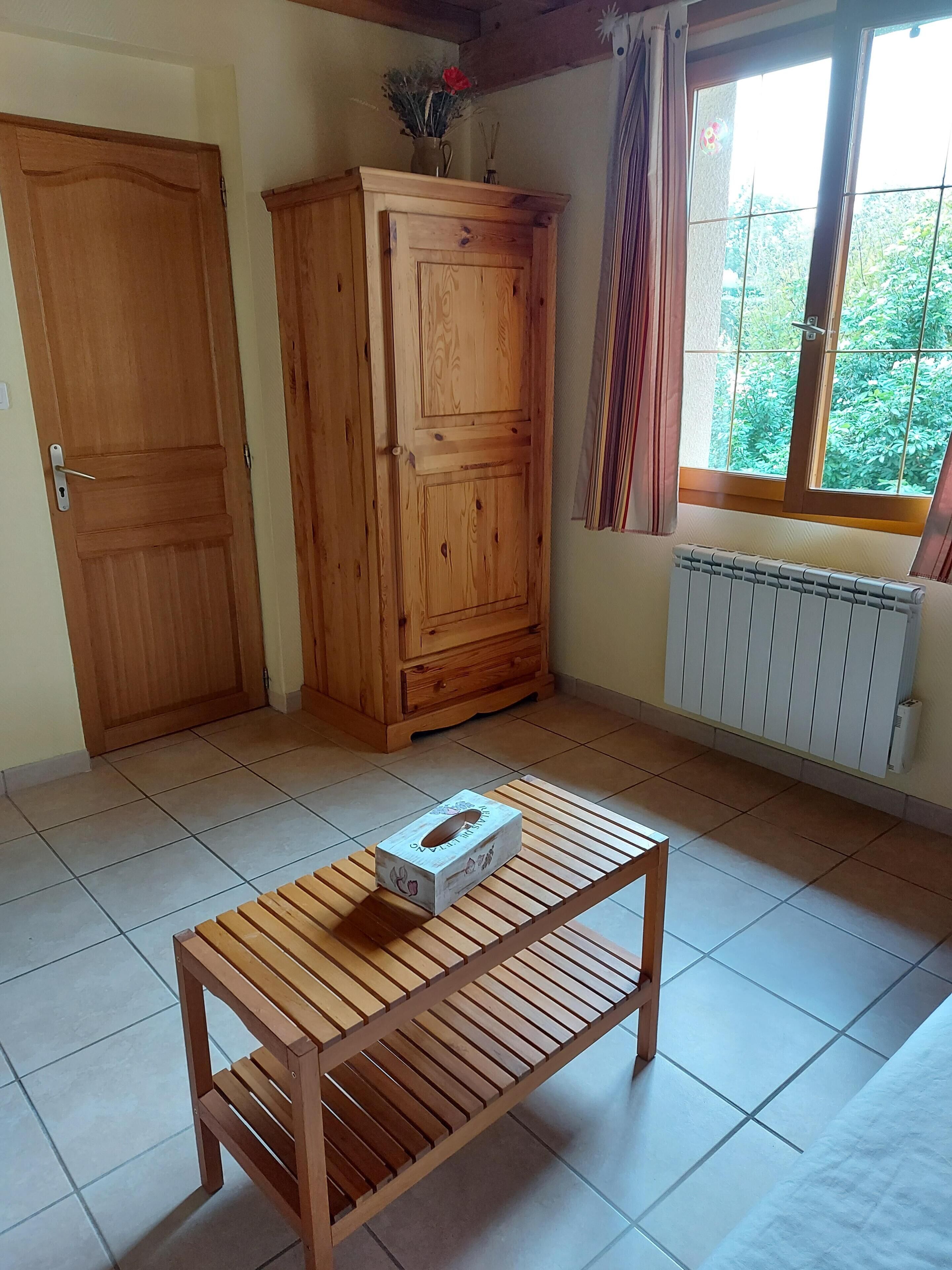 A room with a wooden cabinet, a radiator, and a window with curtains.