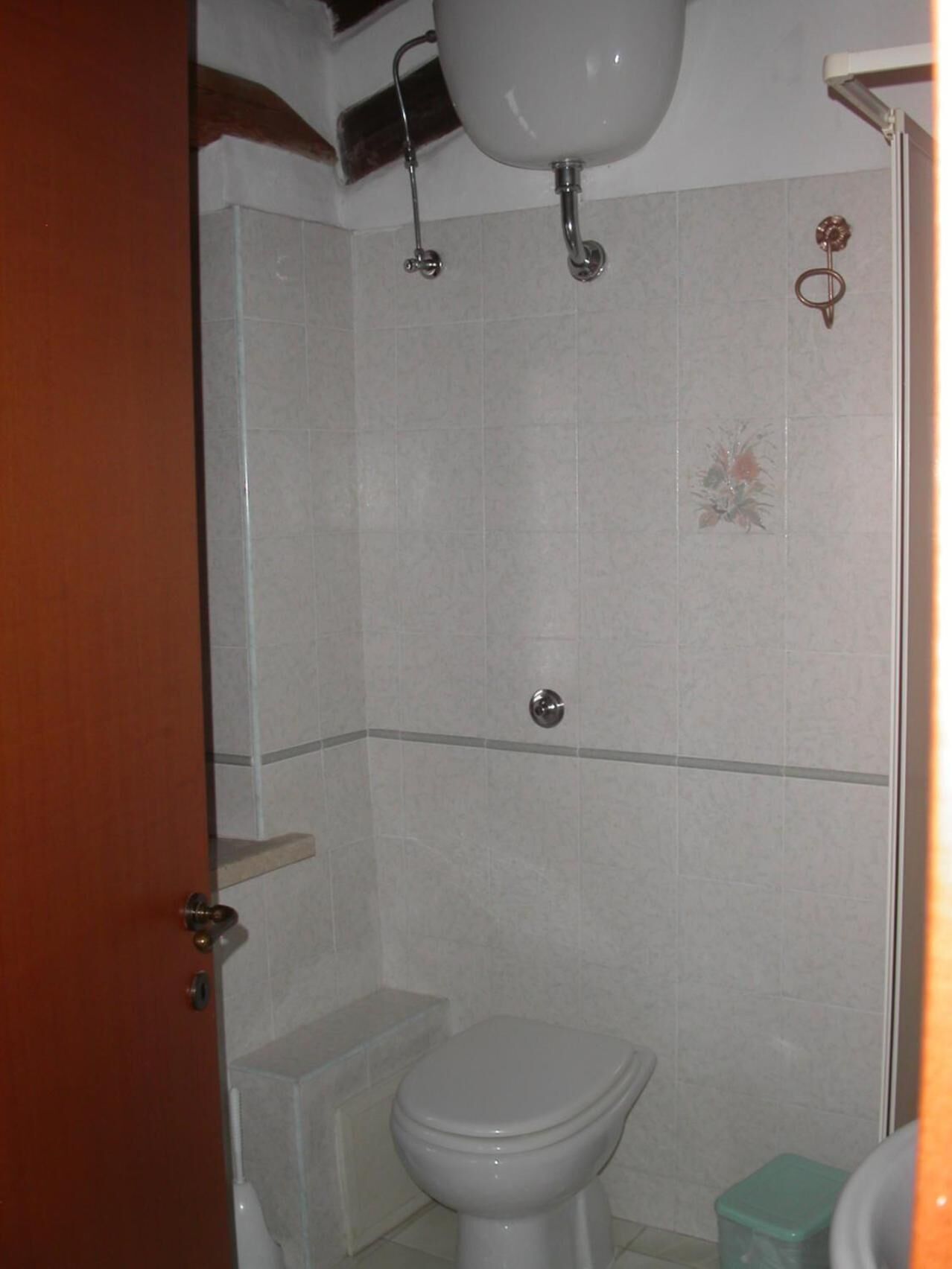 A small bathroom with a toilet, a sink, and a shower.