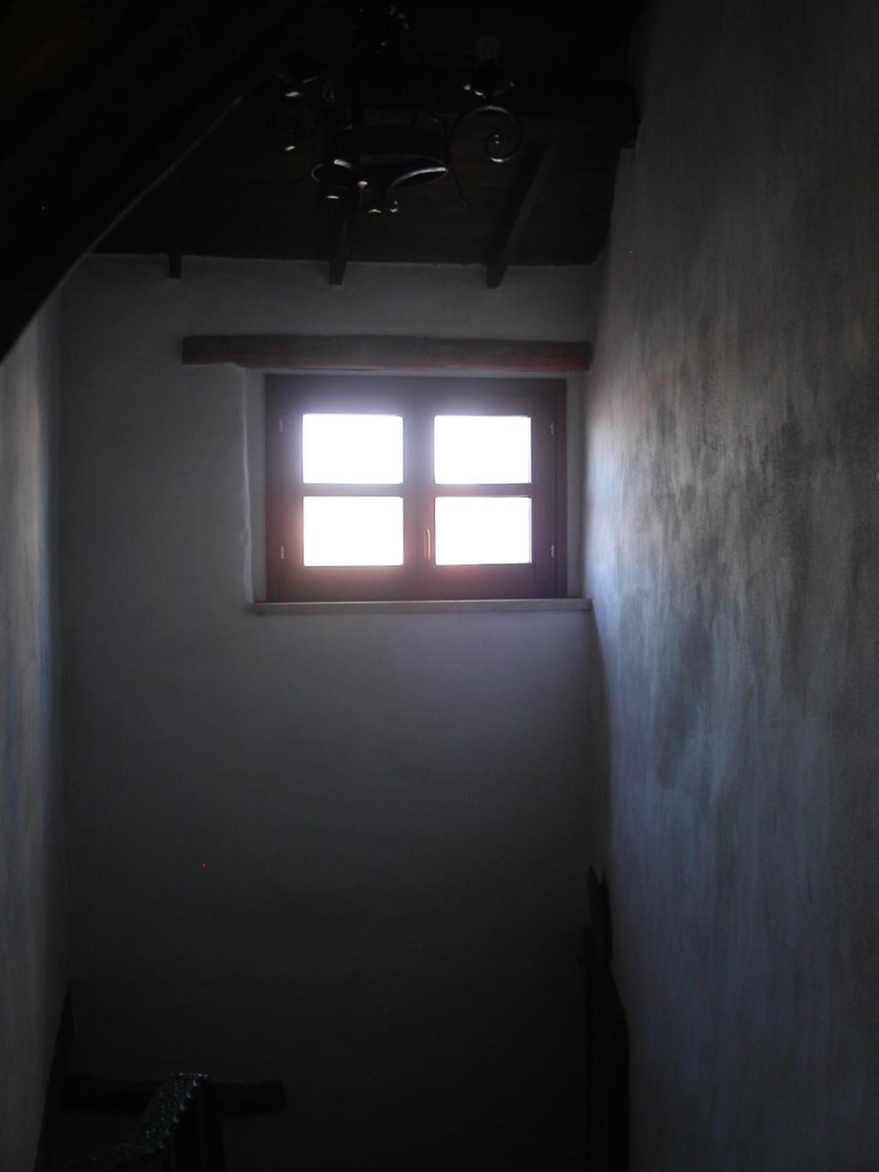 A narrow, dimly lit hallway with a small window at the end.