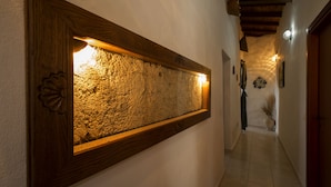 A hallway with a textured wall art piece, a wooden door, and a tiled floor. - Locanda La Rosa (Pauli Arbarei)