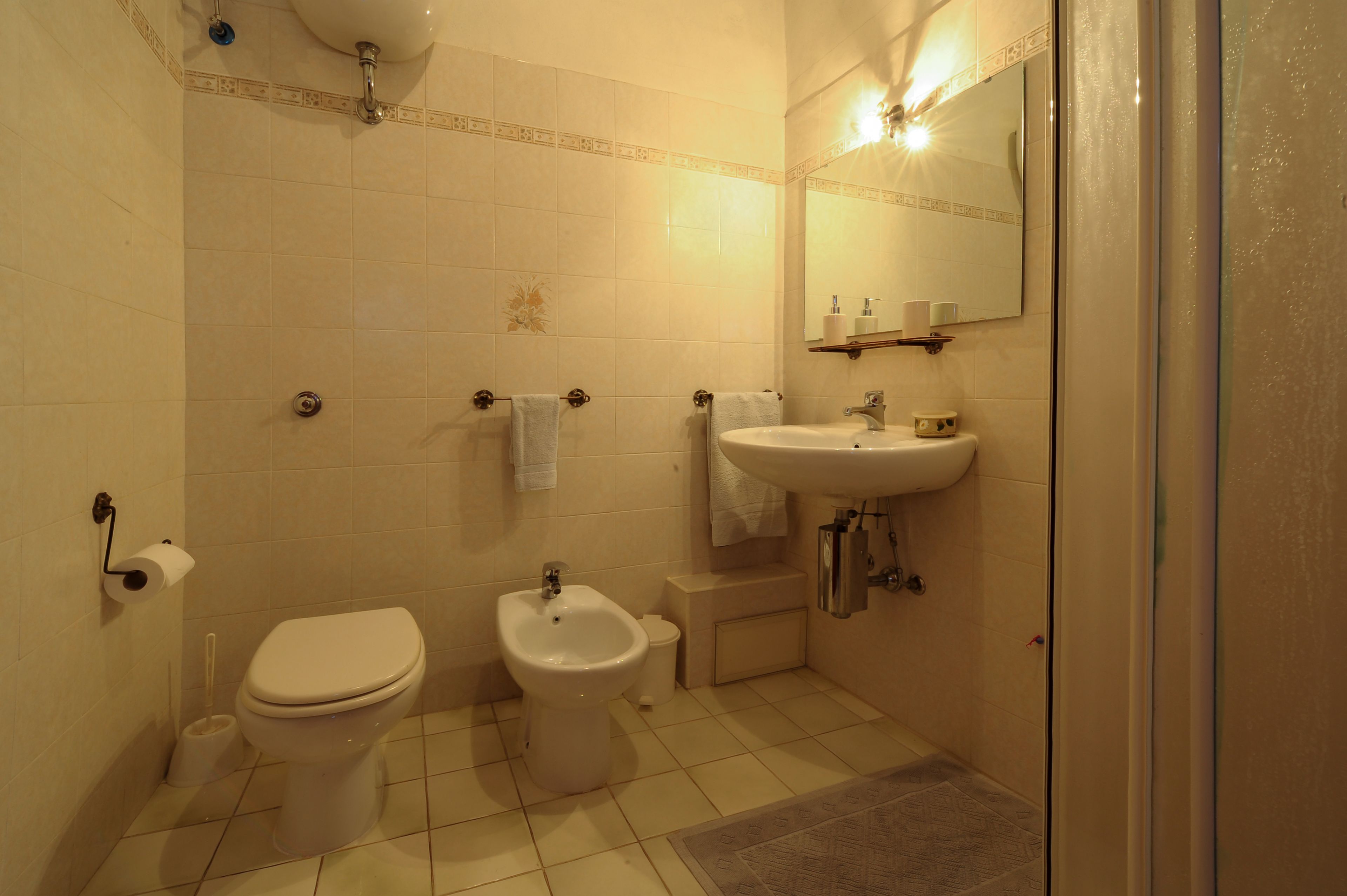 Un baño pequeño con inodoro, bidé, lavabo y espejo.