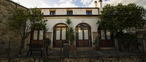 Un edificio con fachada de piedra, ventanas de arco y tejado de tejas.