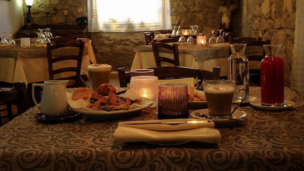 A dining table set with plates of food, glasses, and a pitcher. - Locanda La Rosa (Pauli Arbarei)