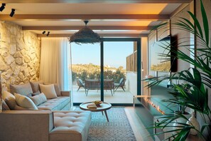 A modern living room with a stone wall, a sofa, a coffee table, and a view of the outdoors. - Zeus Eleva Mirabello Bay (Agios Nikolaos)