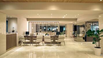 Un interior moderno con un comedor que cuenta con una mesa y sillas de madera, una cocina al fondo y un espejo grande que refleja el espacio.
