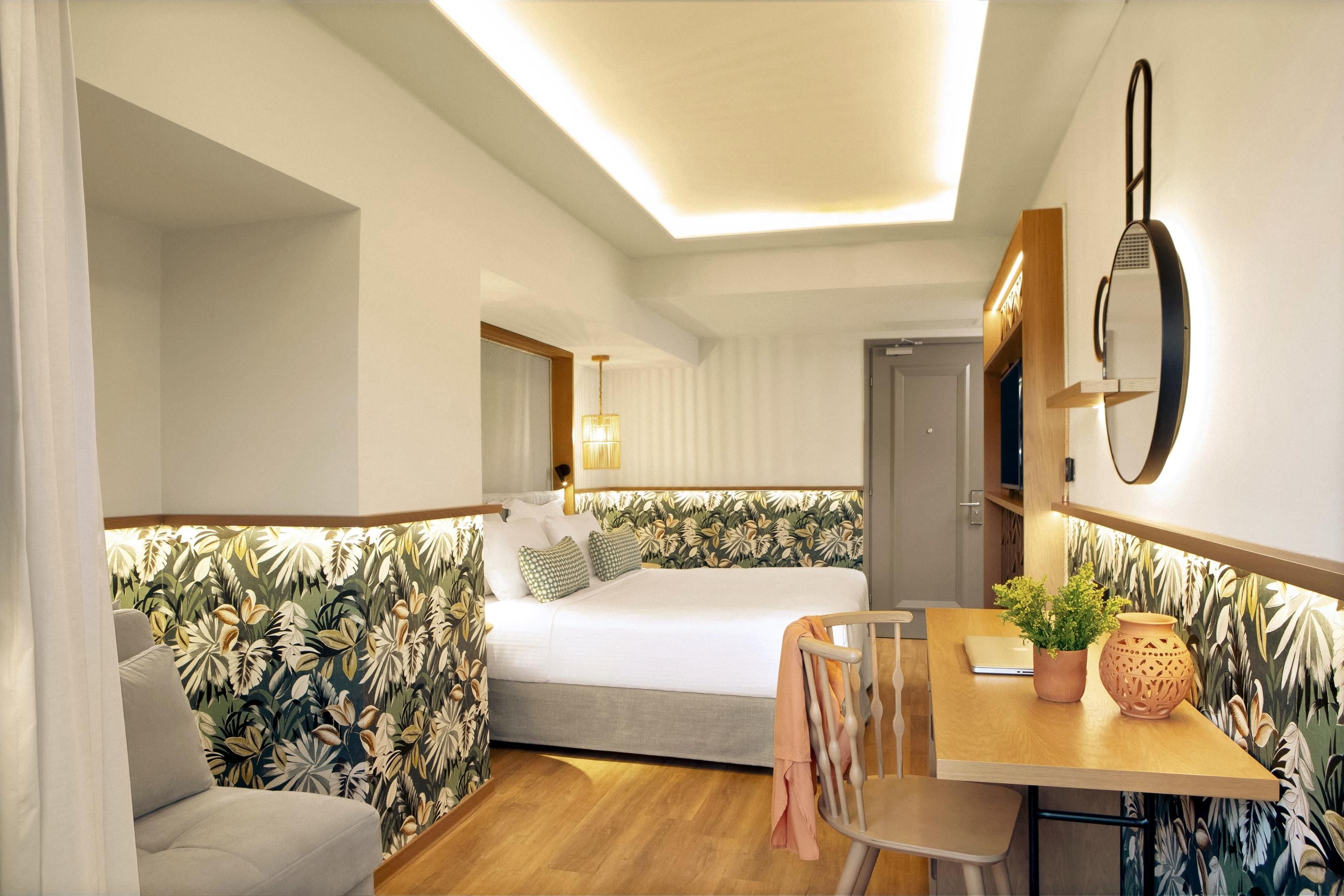 Een moderne hotelkamer met een bed, een bank, een eettafel en een stoel.