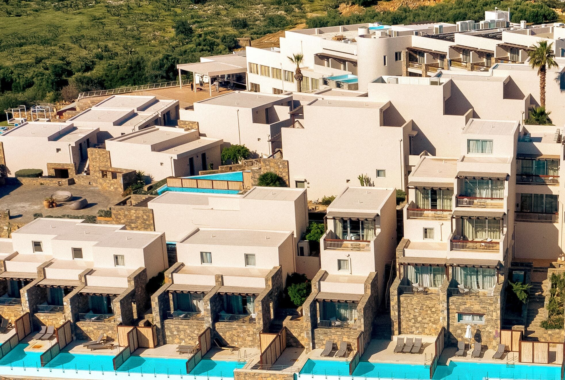 A coastal hotel with multiple balconies, a swimming pool, and a view of the sea.