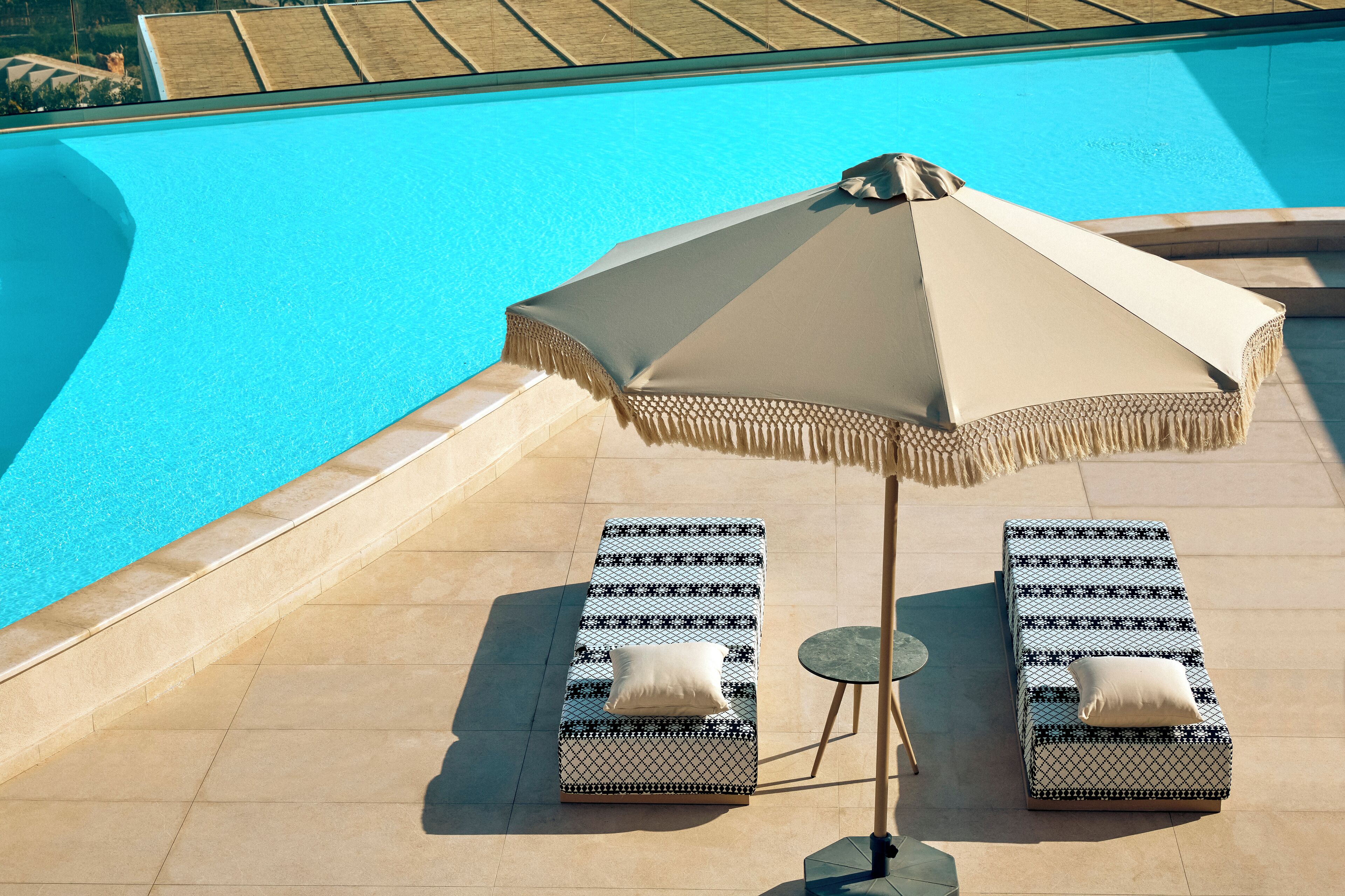 A poolside area with two lounge chairs and a large umbrella.