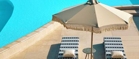 A poolside area with two lounge chairs and a large umbrella.