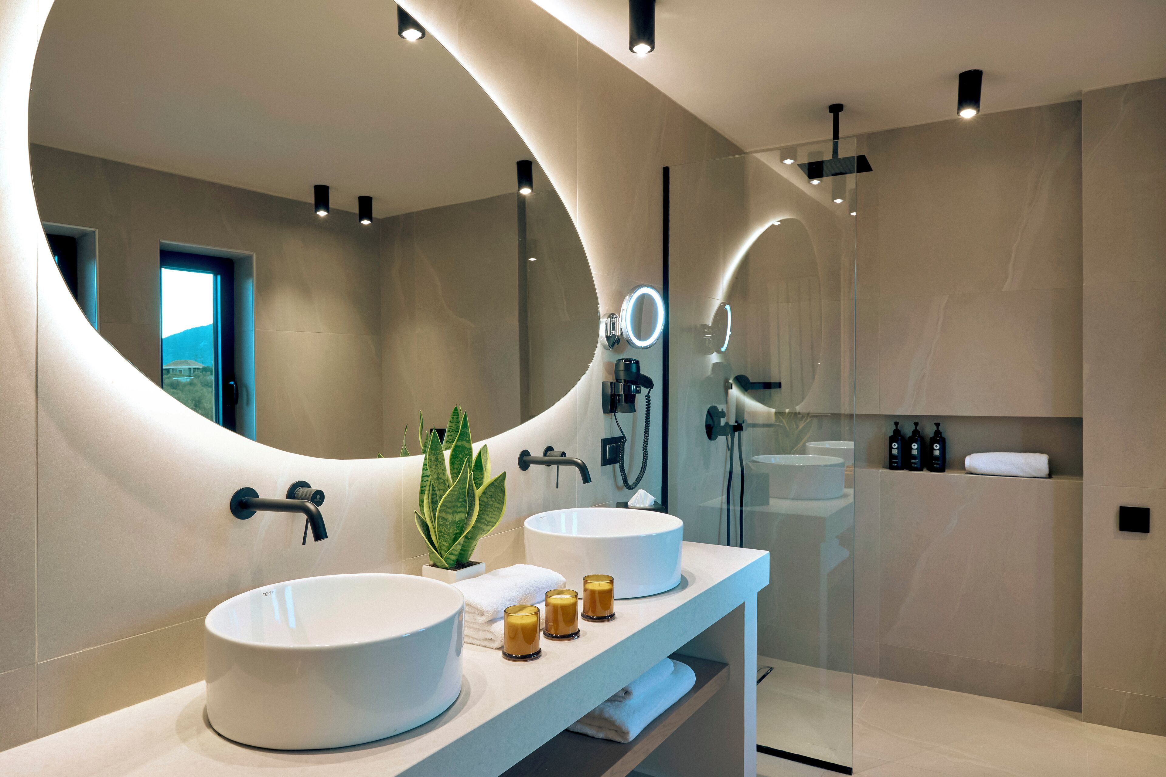 Ein modernes Badezimmer mit zwei großzügigen Waschbecken, einem großen Spiegel und einer Duschkabine.