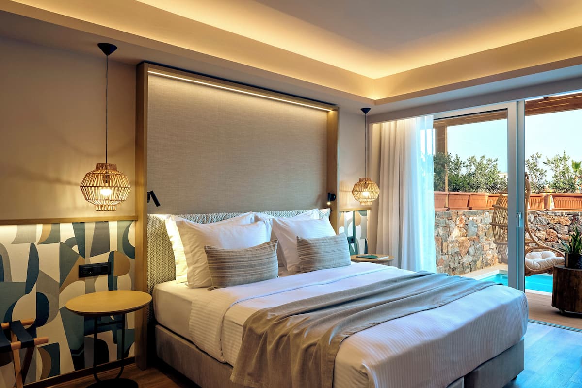 Una habitación de hotel moderna con una cama grande, una mesita y vistas a una piscina.