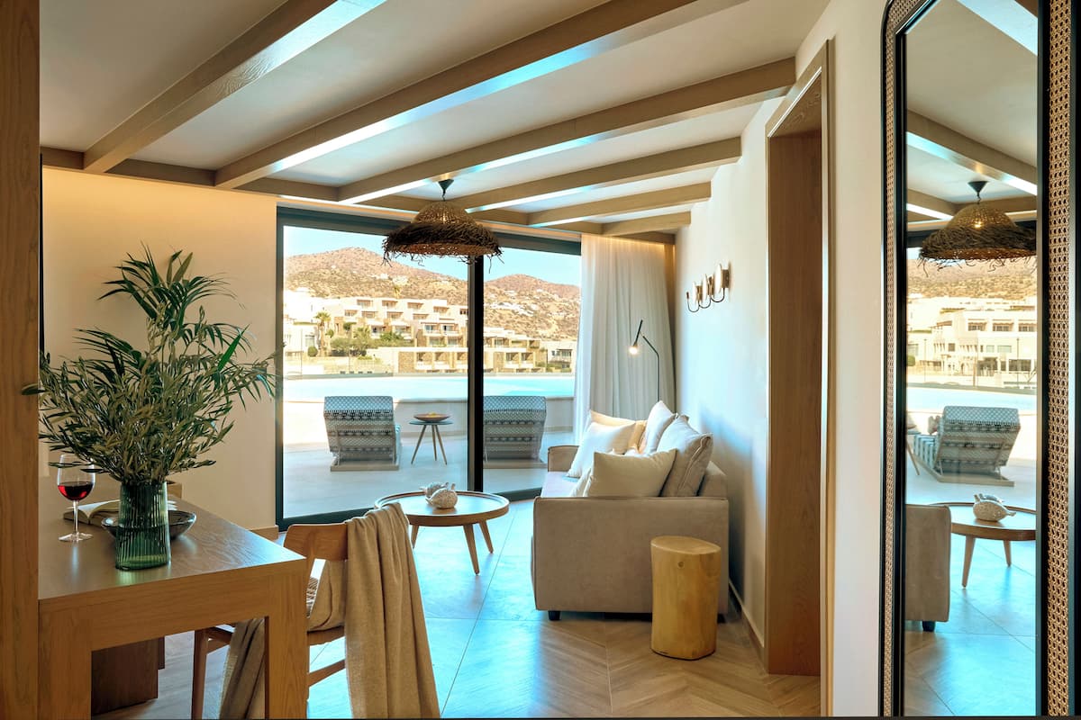 Una sala de estar moderna con un sofá, una mesa de comedor y un ventanal que ofrece vistas a edificios y colinas.