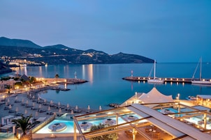 A resort with multiple swimming pools, a marina, and a mountainous backdrop.