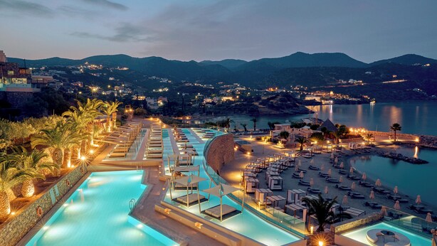 Un complexe hôtelier doté d’une piscine, de chaises longues et offrant une vue sur le paysage environnant.