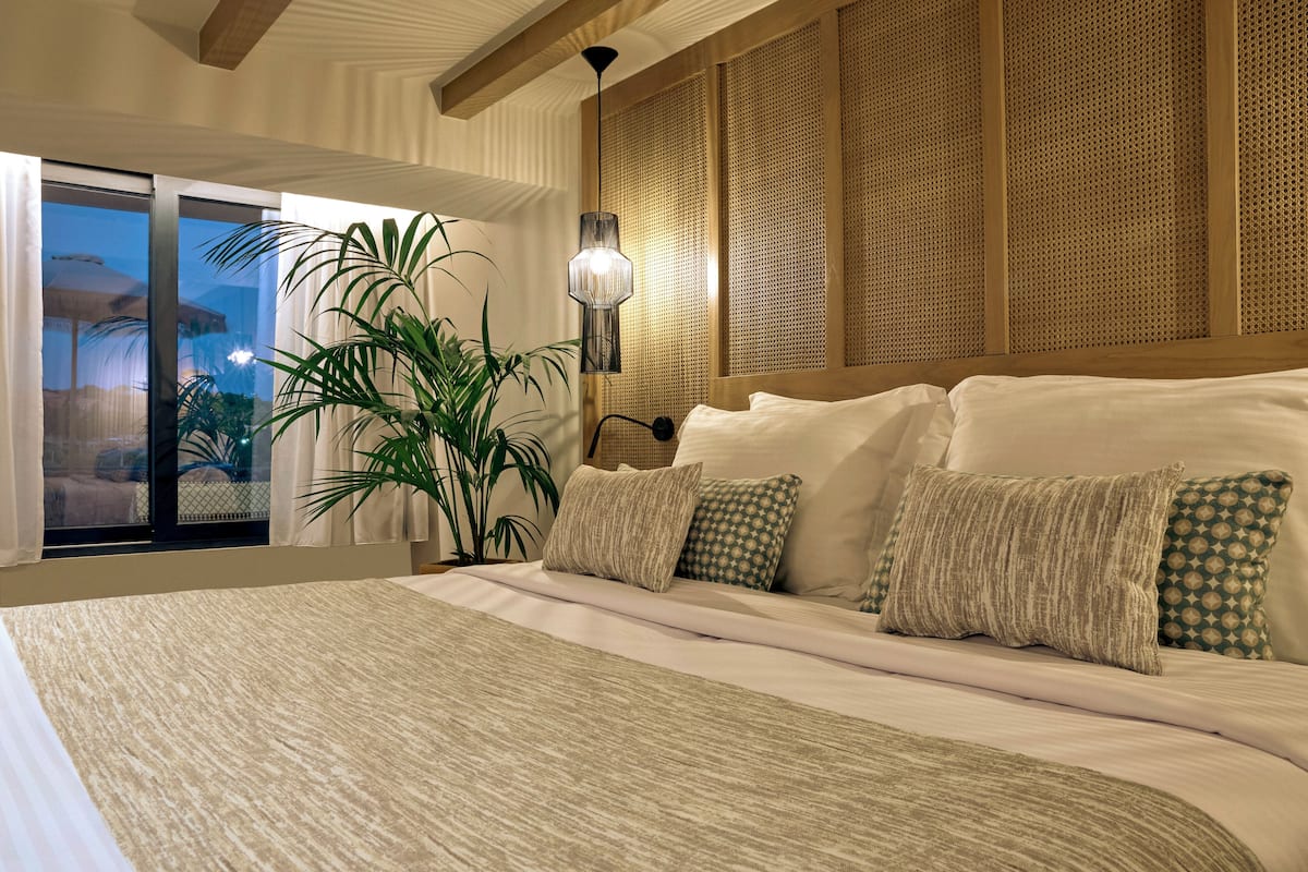 Un dormitorio con una cama grande, una planta en maceta y vistas al exterior.