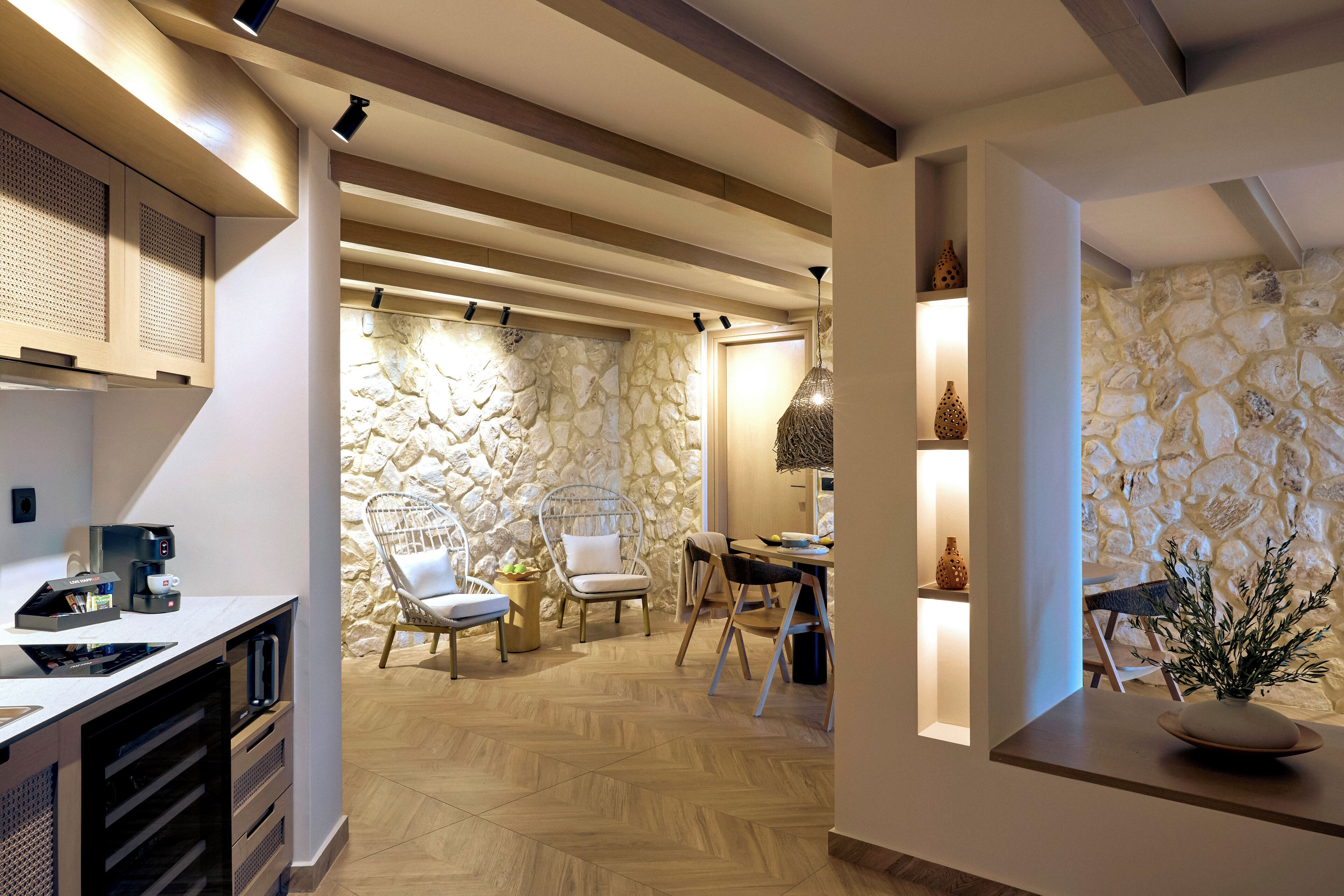 A modern kitchen with a stone wall, wooden beams, and a dining area with chairs and a table.
