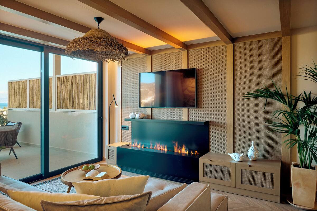 Una sala de estar moderna con chimenea, asientos cómodos y un televisor grande en la pared.
