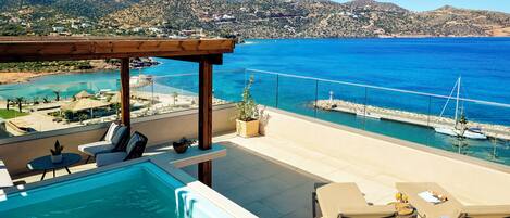 A rooftop pool area with a view of the sea and mountains.