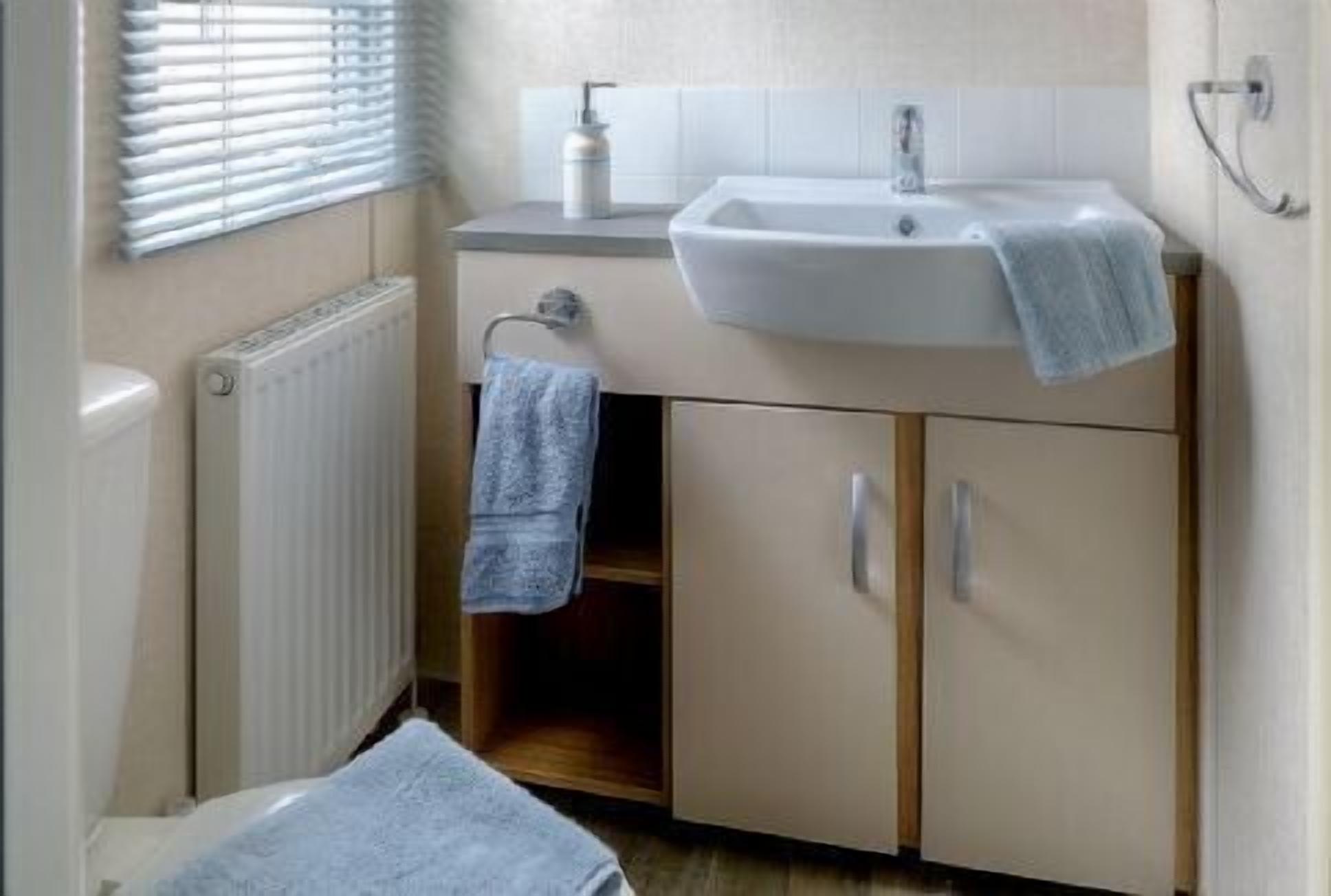 A small bathroom with a sink, a towel rack, and a radiator.