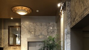 Eine Lobby mit Marmorwänden, einem runden Glastisch mit Pflanze, einer Treppe und einem Rauchmelder.