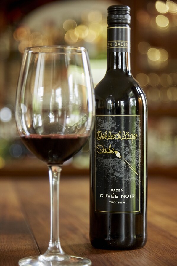 A bottle of Oechsläger Stube wine next to a glass filled with the same wine.