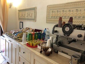 Zona de bufé con diversos alimentos, bebidas y una máquina de café.