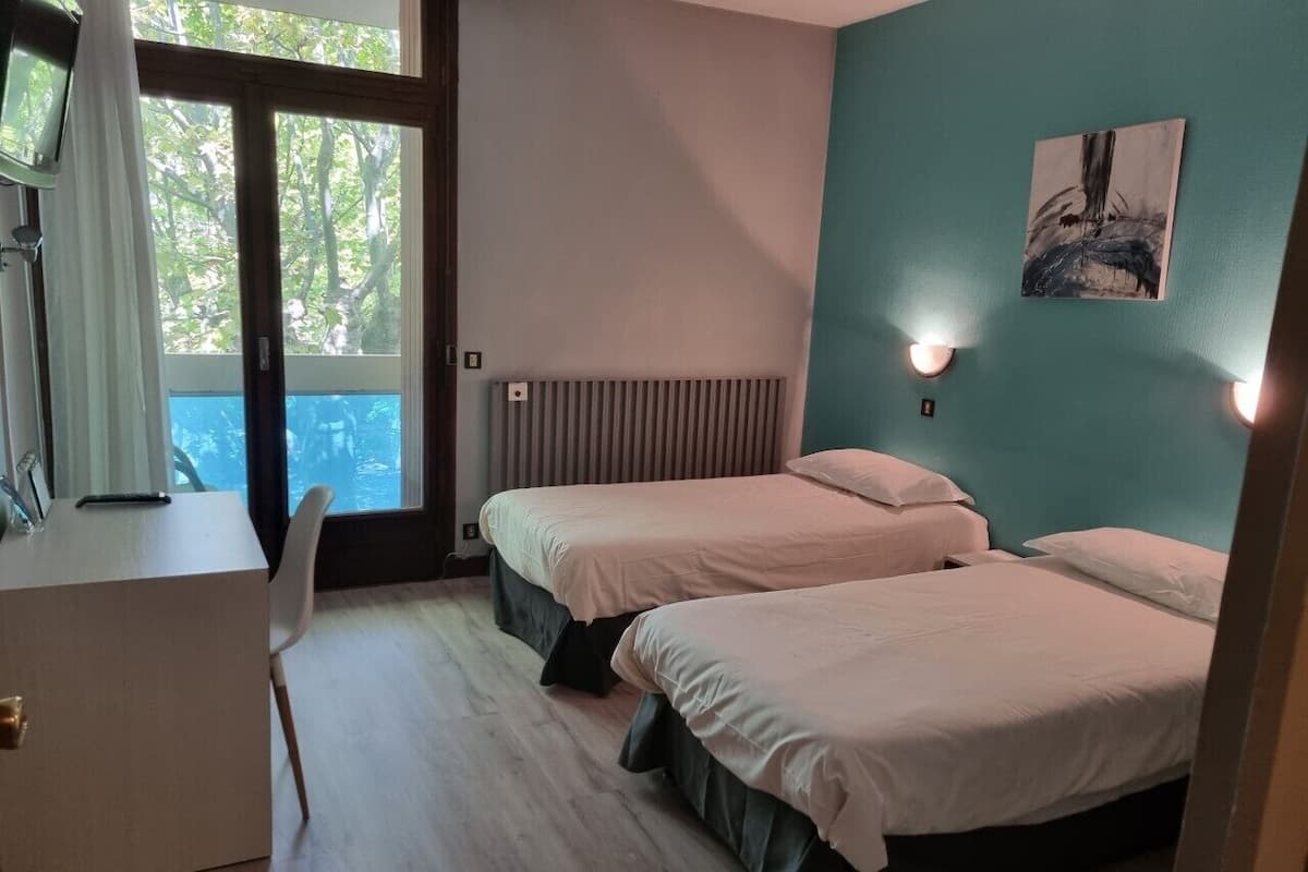A room with two beds, a desk, and a radiator.
