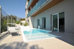 Een buitenzwembad, ligstoelen bij het zwembad