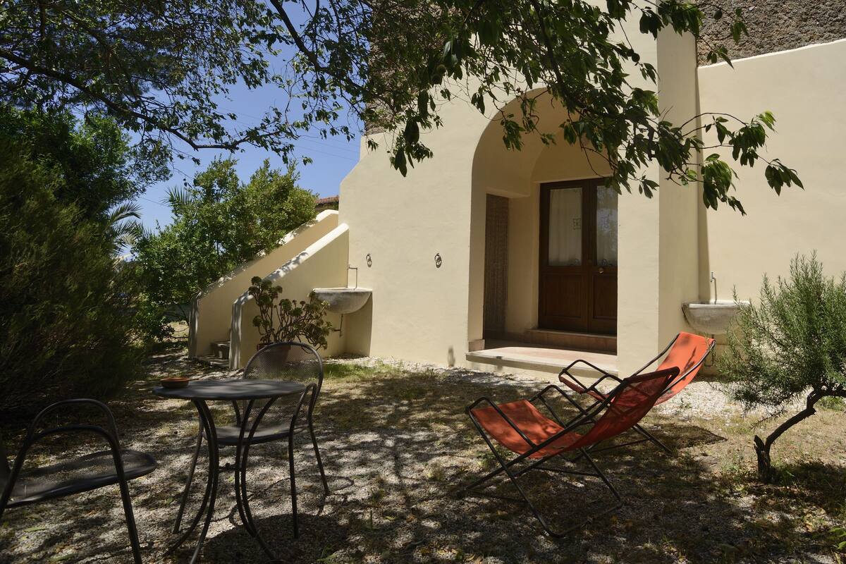 Eine Außenpatio mit Tisch und Stühlen, einem kleinen Brunnen und einem Gebäude mit Tür und Fenster.