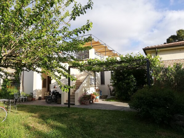A courtyard with a staircase leading to a balcony, surrounded by greenery and potted plants. - Casa del Geco (Capaccio-Paestum)