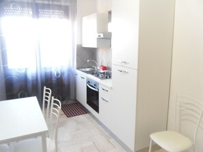 A small kitchen with a white table, chairs, and a sink. - B&B Italia (Milis)